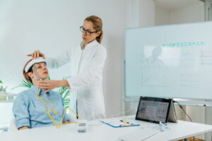 Woman wearing a biofeedback device on her head, illustrating the use of biofeedback for bruxism, a technique for managing teeth grinding and jaw clenching.
