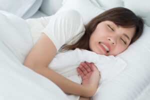 sleeping woman in bed suffering long term bruxism